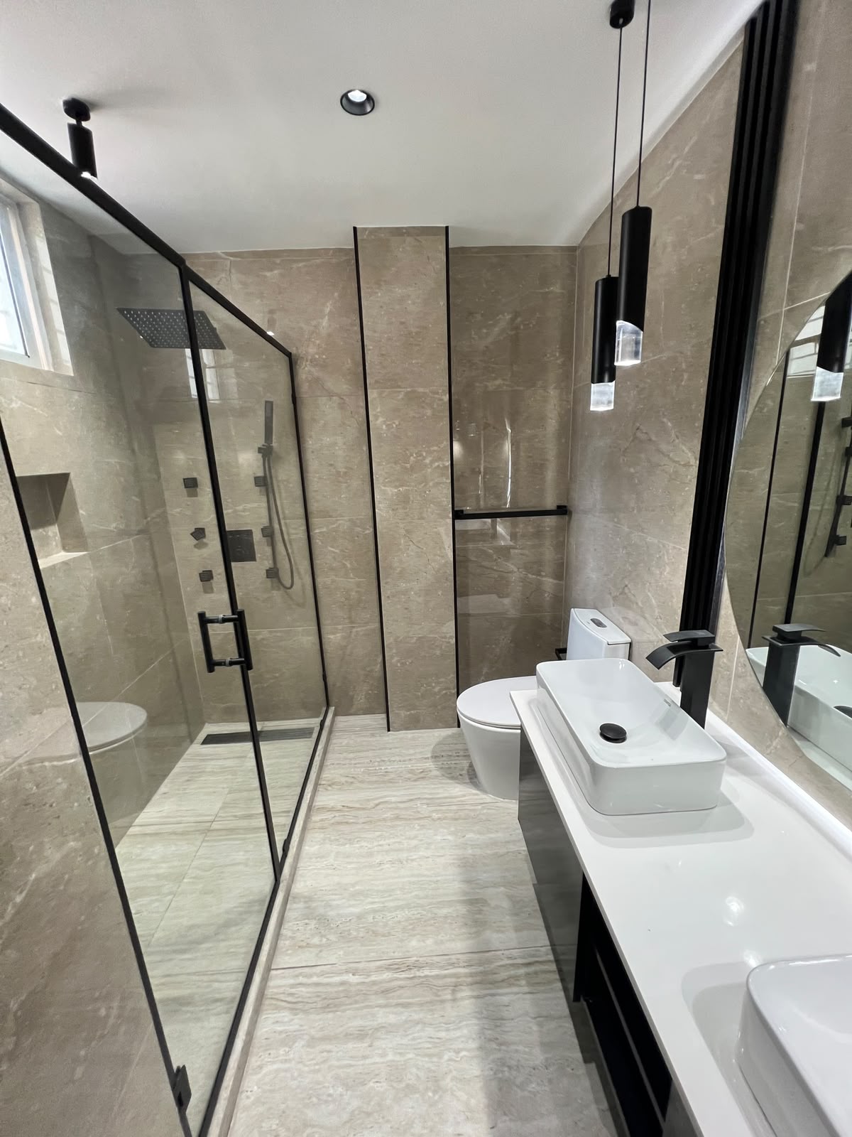 Baño en travertino con mampara negra