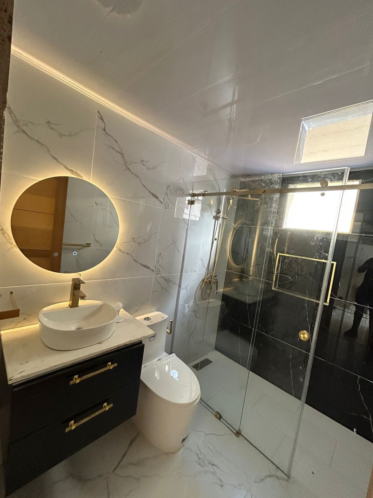 Baño en mármol y negro con herrajes dorados